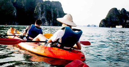 A stunning view of Ha Long Bay with a cruise boat surrounded by towering limestone islands and clear blue waters.